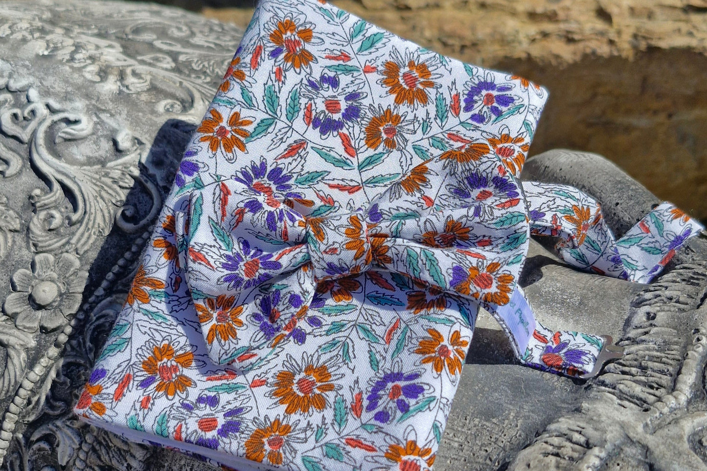 ensemble noeud papillon et pochette de costume assortis, cousu dans un tissu de récupération dont la composition exacte est inconnue. Motifs fleurs abstraites de couleurs oranges, parme et feuillages verts sauge