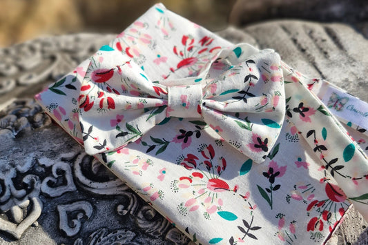 ensemble composé d'un nœud papillon et de sa pochette fleurie assortie. fleurs éparses tons rouges sur fond blanc